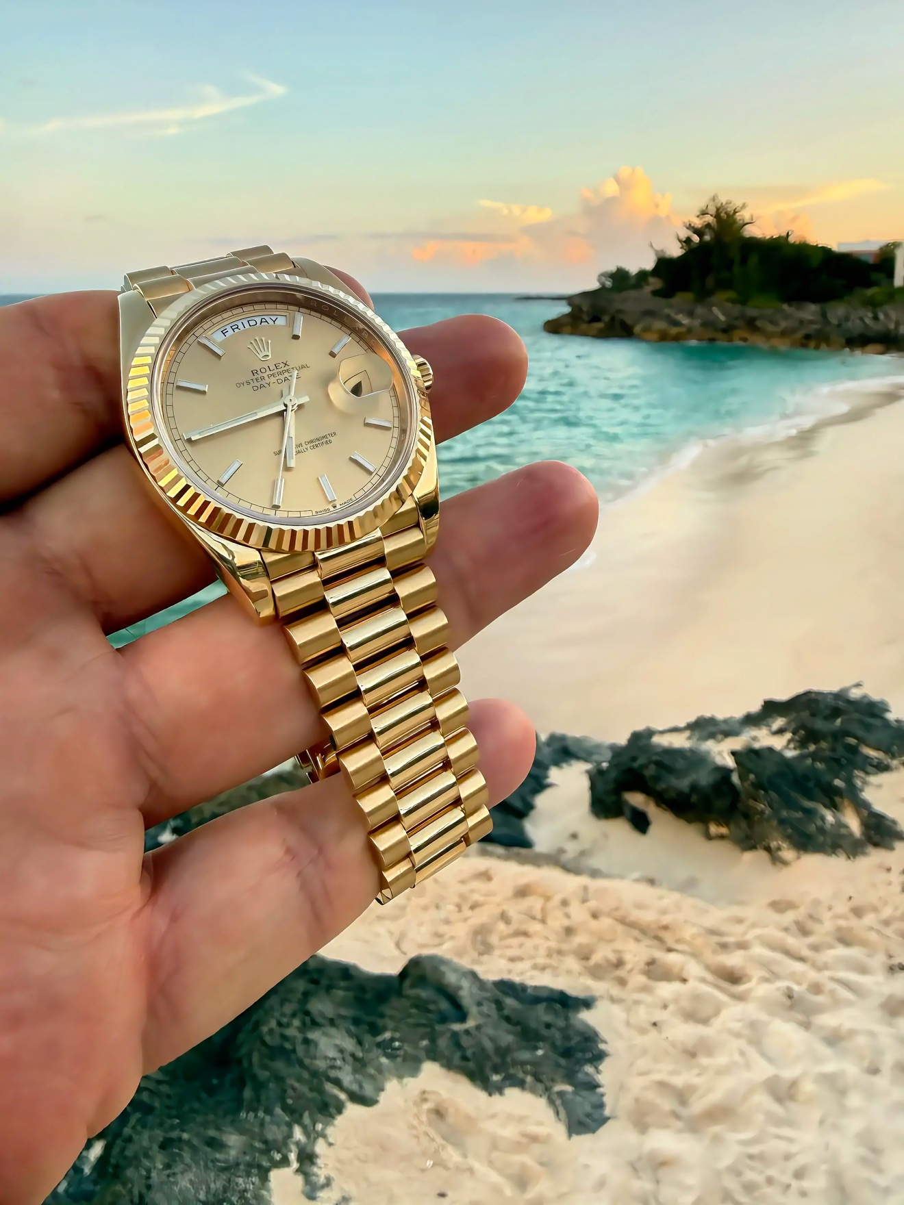 2022 Rolex Day-Date 40 in yellow gold with a champagne dial, fluted bezel, and President bracelet held at the beach